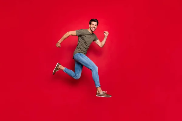 Полноразмерное фото чемпиона парень прыжки высоко пришел первым, чтобы закончить носить повседневную одежду изолированы на красном фоне — стоковое фото