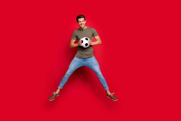 Крутой парень прыгает высоко держа мяч, празднуя первое место соревнований носить случайный наряд изолированы на красном фоне — стоковое фото