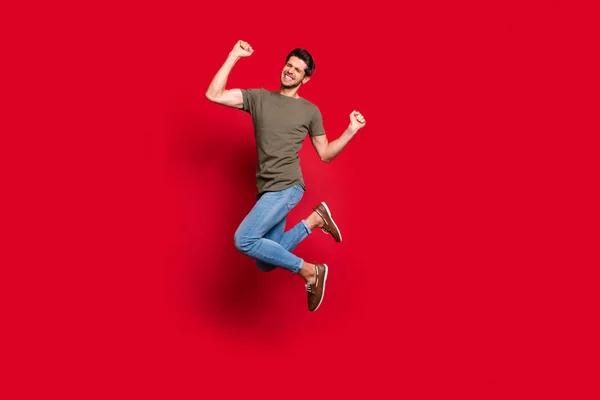 Foto de cuerpo entero del tipo increíble saltando alto éxtasis ganar desgaste traje casual aislado sobre fondo rojo — Foto de Stock
