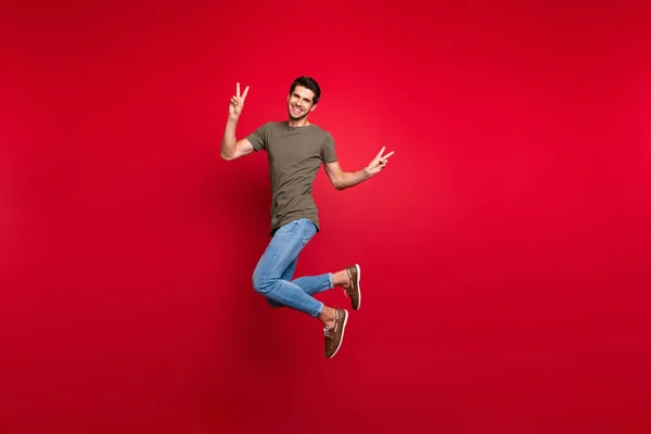 Foto de longitud completa de un tipo increíble saltando alto mostrando símbolo de v-signo de desgaste traje casual aislado sobre fondo rojo — Foto de Stock