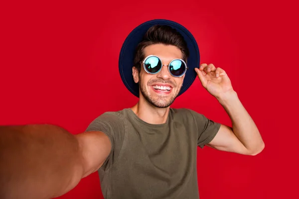 Foto di viaggiatore ragazzo fare selfie indossare vintage cappello sole specs e grigio t-shirt isolato su sfondo rosso — Foto Stock