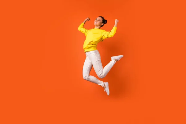 Full length photo of cheerful lovely lady raise fists smiling jumping dressed white pants trousers isolated over orange background — Stock Photo, Image