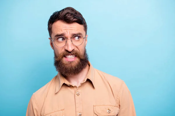 Photo rapprochée d'un homme frustré qui porte des lunettes de vue marron isolées sur fond bleu — Photo