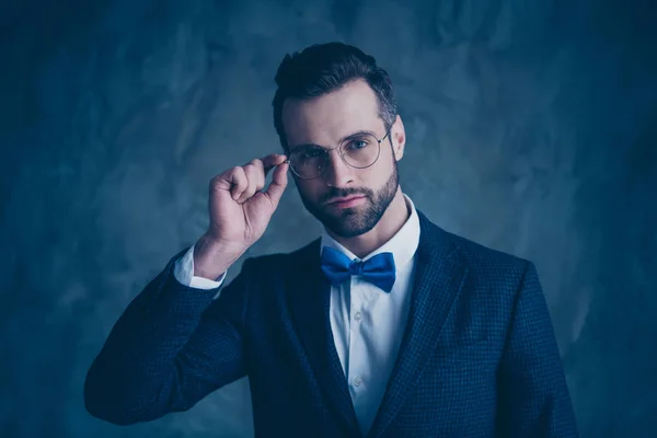Portrait of charming man touching his specs wearing blue bowtie isolated over grey background — Stock Photo, Image
