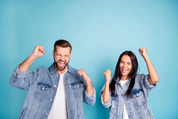 Retrato de pessoas alegres gritando sim levantando os punhos fechando os olhos usando jeans jeans isolados sobre fundo azul — Fotografia de Stock