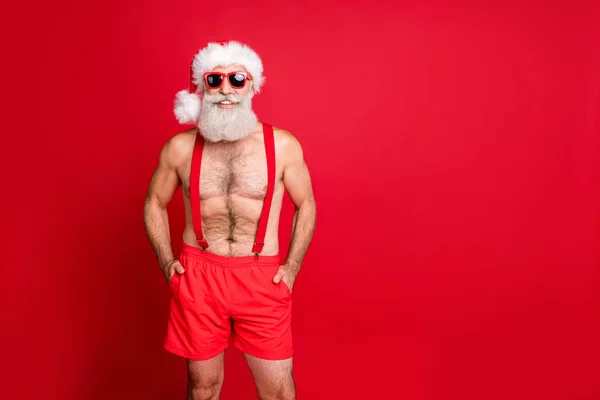 Porträtt av hans han trevlig attraktiv säker skäggiga muskulös anfall glad funky gråhåriga man håller händerna i fickor Christmastime resa isolerade över ljusa levande lysa röd bakgrund — Stockfoto