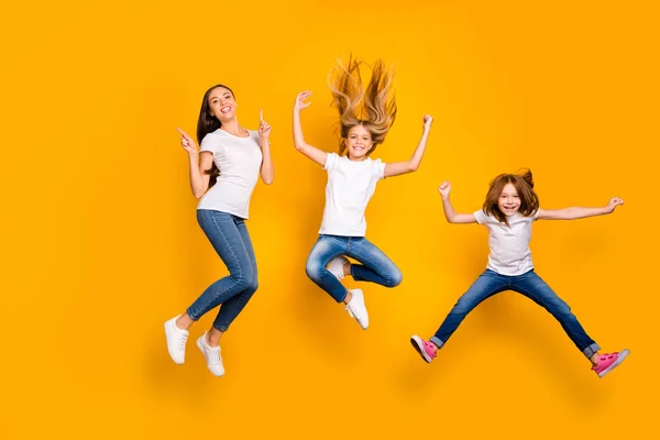 Foto de longitud completa de tres señoras divertidas saltando ropa casual de alto desgaste aislado fondo amarillo — Foto de Stock