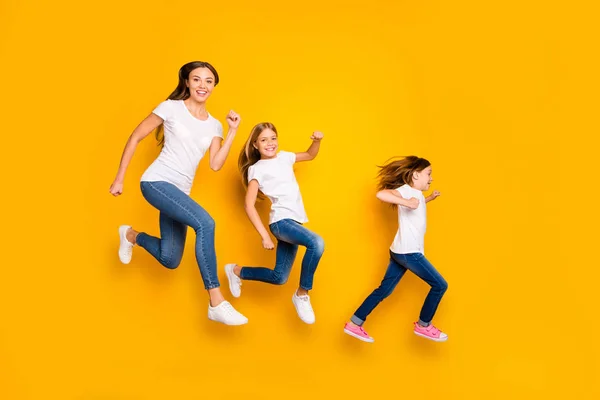 Ganzkörper-Foto von drei Damen springen hoch eiligen Verkauf einkaufen tragen lässige Kleidung isoliert gelben Hintergrund — Stockfoto