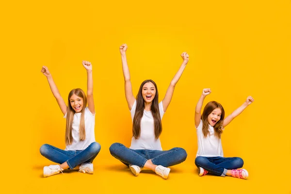 Full body foto van Amazing drie dames zittend vloer opvoeden vuisten omhoog slijtage casual kleding geïsoleerd gele achtergrond — Stockfoto