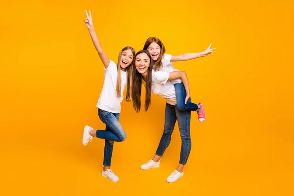 Photo of funky three ladies showing v-sign spending leisure time wear casual clothes isolated yellow background — Zdjęcie stockowe