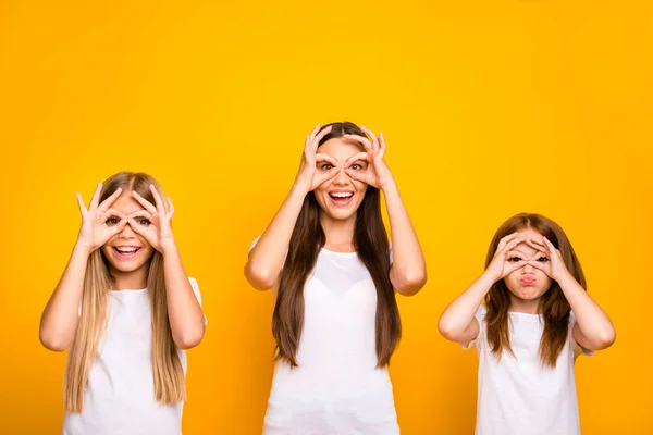 Engraçado três irmãs senhoras de mãos dadas em símbolos okey perto de olhos como especificações usar roupa casual isolado fundo amarelo — Fotografia de Stock