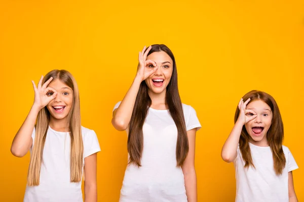 Lustige drei schwester damen halten hände in okey symbole in der nähe auge wie specs tragen casual outfit isoliert gelb hintergrund — Stockfoto