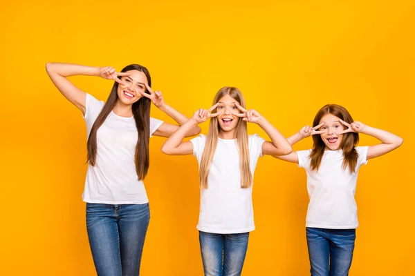 Divertido tres hermanas señoras mostrando v-signo símbolos cerca de ojos desgaste casual traje aislado amarillo fondo — Foto de Stock