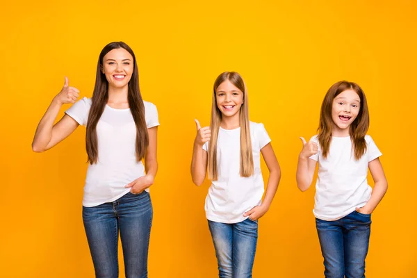 Ganska tre syster damer ge godkännande till testade produkt höja tummen upp slitage casual outfit isolerad gul bakgrund — Stockfoto