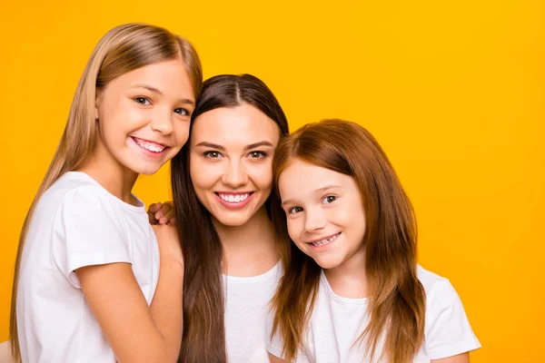 Three pretty ladies of different age hugging each other with love wear casual white t-shirts isolated yellow background — Stock Photo, Image