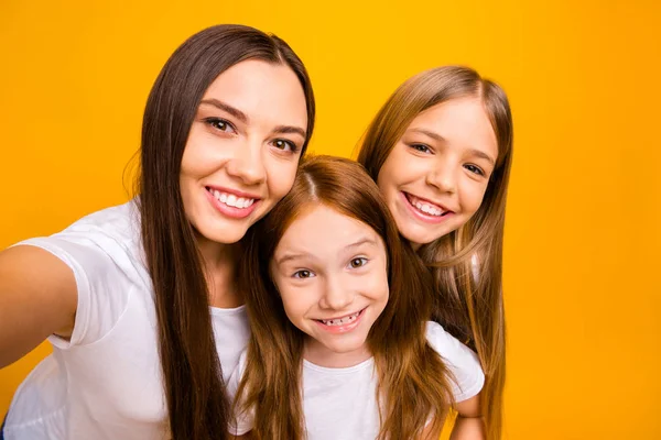 Photo of three sister ladies making funny selfies wear casual white t-shirts isolated yellow background — Zdjęcie stockowe