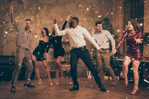 Volledige lengte foto van vrolijke multinationale vrienden dansen geniet van kerstfeest x-mas vakantie in huis met confetti Nieuwjaar verlichting binnenshuis — Stockfoto