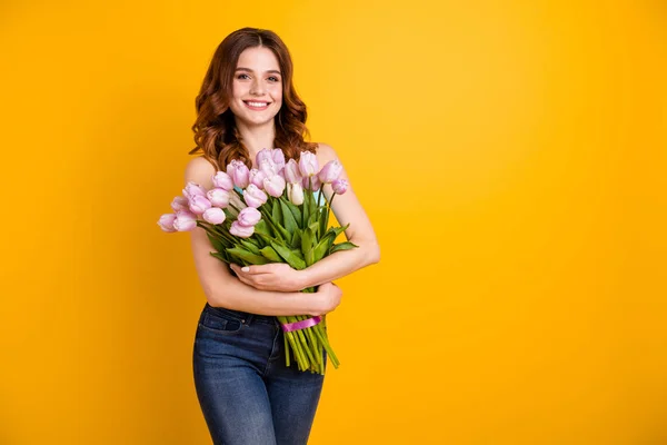 Conceito de frescura de primavera. Foto de uma senhora incrível segurando um monte grande de tulipas rosa em mãos usar tanque-top isolado fundo amarelo — Fotografia de Stock