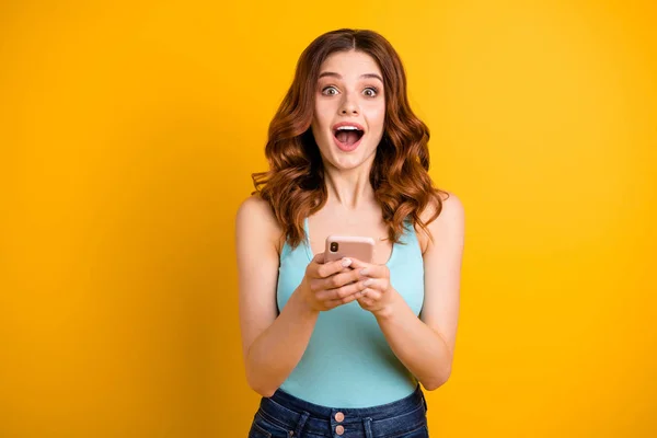 Photo of excited lady with open mouth holding telephone in hands wear blue tank-top isolated yellow background — Stock Photo, Image