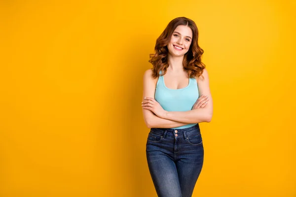 Foto de bonito agradável alegre linda namorada linda com as mãos dobradas sorrindo alegremente vestindo jeans turquesa tanque-top isolado com fundo de cor vibrante amarelo — Fotografia de Stock