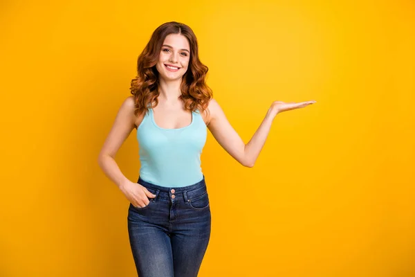 Foto de bonito ondulado encaracolado alegre fascinante namorada bonita doce vestindo jeans turquesa-top jeans segurando algo invisível com a mão enquanto isolado com fundo de cor vibrante — Fotografia de Stock