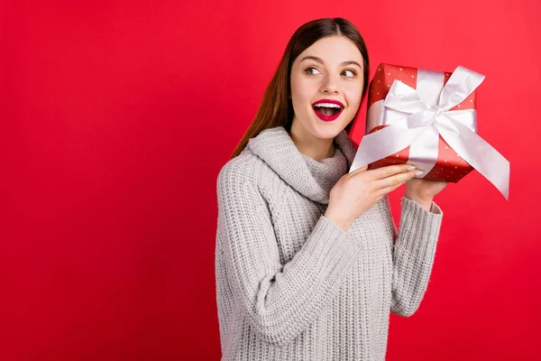 Bonita dama con gran caja de regalo preguntándose qué ropa interior de punto suéter aislado fondo rojo —  Fotos de Stock