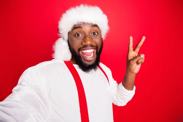 Close up photo of excited black christmas father in xmas hat enjoying memory take selfie making v-signs wearing white jumper isolated over red background — Φωτογραφία Αρχείου