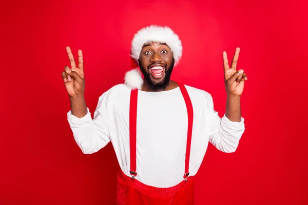 Porträt eines fröhlichen afroamerikanischen Weihnachtsmannhutes, der V-Zeichen setzt und einen weißen Pullover auf rotem Hintergrund trägt — Stockfoto