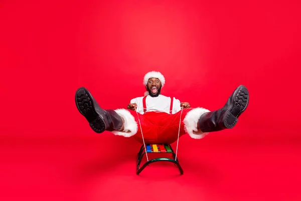 Pełna długość Zdjęcia Afryki mieszane wyścigu Santa w Nicholas Cap krzyczeć sankach noszenie spodnie spodnie biały sweter na białym tle na czerwonym tle — Zdjęcie stockowe