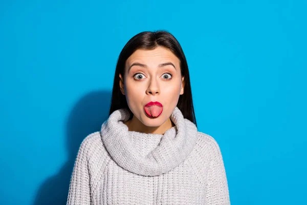 Malá legrační dáma, která neslušně vystrčí jazyk z úst, nosí pletený pulmilenec izolované modré pozadí — Stock fotografie
