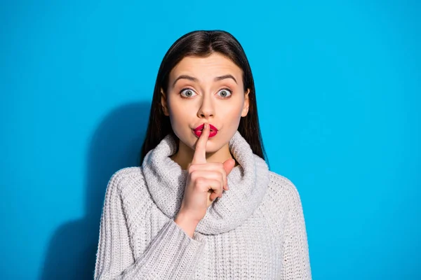 Foto de cerca de la señora asustada mostrando el dedo índice cerca de la boca mirando fijamente usando jersey gris aislado sobre fondo azul — Foto de Stock