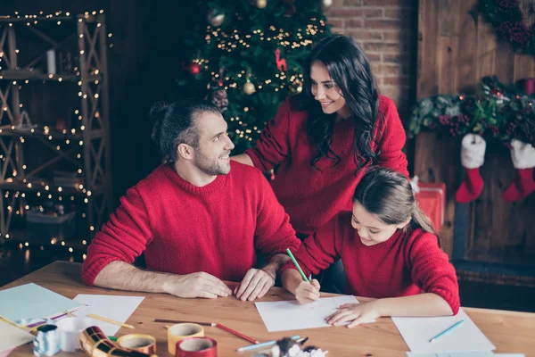 Noel avond concept. Foto van gelukkig mooi comfort charmant mooi stralende mensen Mama Mama Daddy dragen rode jumpers met dochter schoolmeisje schilderij iets op vel papier — Stockfoto