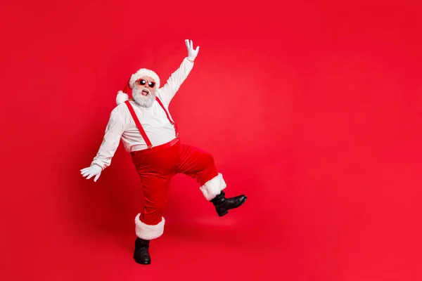 Foto de cuerpo entero de grasa sobrepeso Santa Claus con gran vientre divertido abdomen tienen gafas bailando con pantalones pantalones pantalones botas aisladas sobre fondo rojo — Foto de Stock