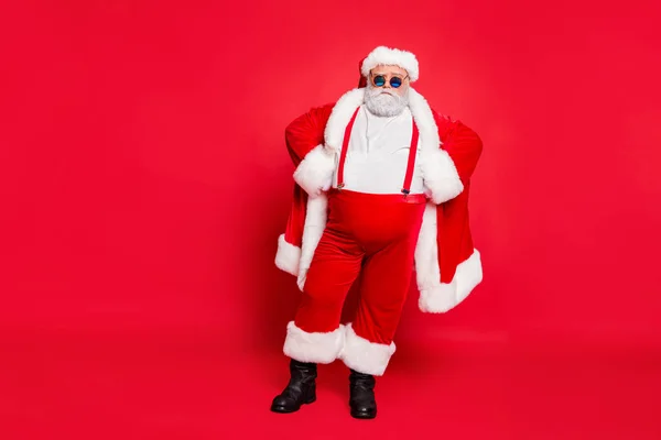Pełna długość Zdjęcia ścisłego Świętego Mikołaja zły facet tłuszczu nadwagą z dużym brzuchu zdecydować wybrać niegrzeczne dzieci mają stylowe okulary kapelusz stojący izolowane na czerwonym tle — Zdjęcie stockowe