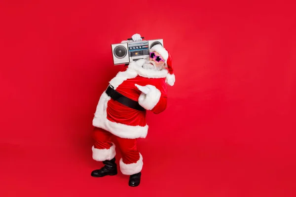 Full size photo of cool old stylish trendy santa claus in eyewear eyeglasses dancing holding audio sound cassette isolated over red background — Stock Photo, Image