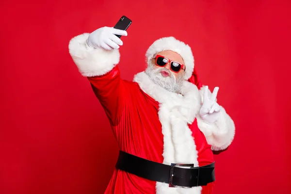 Πορτρέτο του αυτός ωραίος ελκυστικός χαρούμενος χαρούμενο θετικό φλερτ με μούσι Santa θυμωνες τα χείλη κάνοντας selfie έχοντας τη διασκέδαση δείχνοντας v-υπογραφή απομονωθεί πάνω από φωτεινό έντονο κόκκινο φόντο — Φωτογραφία Αρχείου