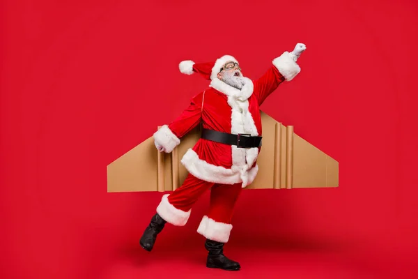 Full storlek foto av förvånad äldre superhjälte jul fader imponerad av flyga upp Turbo hastighet av hans magiska föreställa raket vingar Scream OMG bära mössa hatt isolerade över röd bakgrund — Stockfoto
