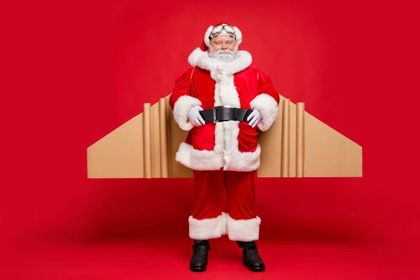 Pronto para o voo. Foto de comprimento total de Papai Noel charmoso fresco com cartão de avião imaginar asas usar cinto de fantasia de fada isolado sobre fundo de cor vermelha — Fotografia de Stock