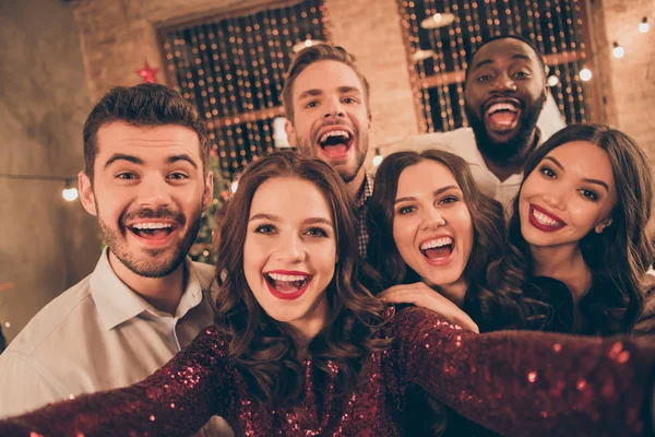 Arkadaşlarının neşeli çok ırklı grup gülmek çığlık yakın fotoğraf noel gecesi x-mas parti de eğlenmek resmi giyim içinde yeni yıl ışıkları ile evde selfie yapmak — Stok fotoğraf