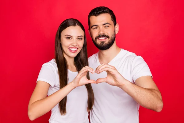 Foto van charmante casual stijlvolle schattig mooie fascinerende mooie echt genoten twee mensen tonen hart vorm met hun handen terwijl geïsoleerd met rode achtergrond — Stockfoto