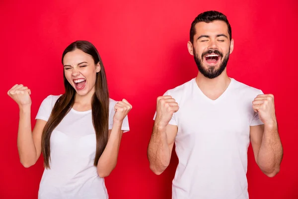 Foto de dos hermosas personas guapas que parecen haber ganado algunas competiciones juntos triunfando demostrando juego en equipo mientras están aislados sobre fondo rojo —  Fotos de Stock