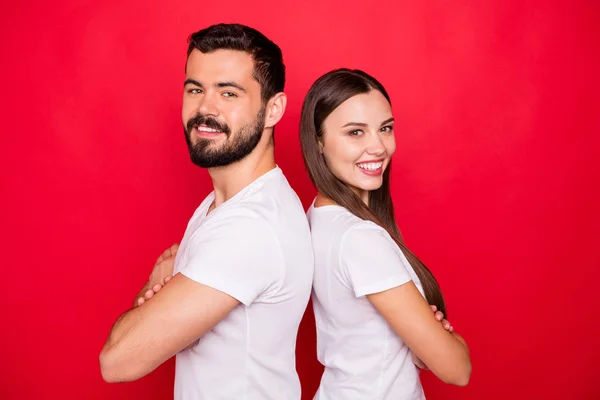 Zdjęcie dwóch casual modny piękny przystojny całkiem miły wesoły ludzie stojący z powrotem do siebie nawzajem noszenie białego t-shirty zespołu, a izolowane z czerwonym tle — Zdjęcie stockowe