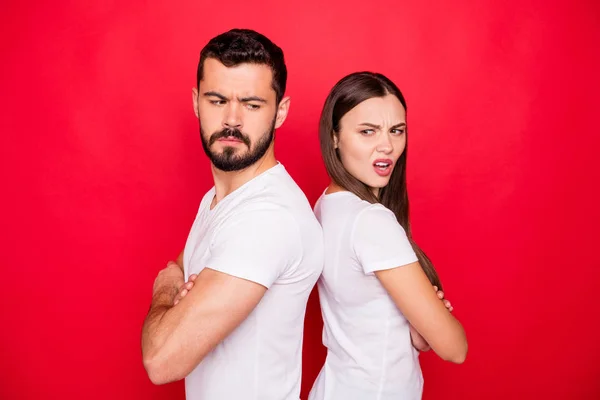 Photo of sad upset unhappy trendy stylish white people wearing t-shirts offensively looking at each other while isolated with red background — Stock Photo, Image