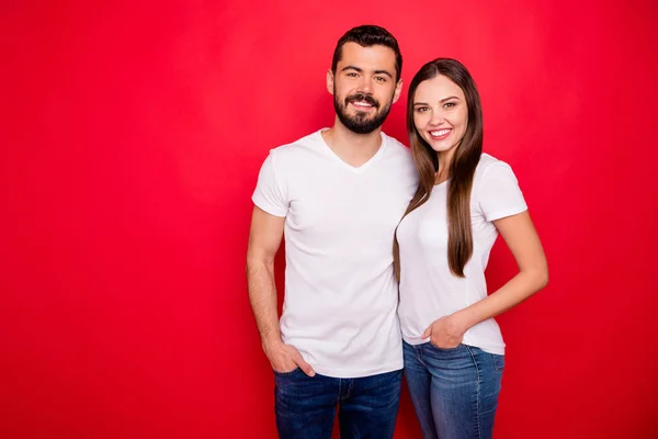 Φωτογραφία του γοητευτικό χαριτωμένο όμορφο όμορφο ζευγάρι που φοράει τζιν ντένιμ λευκό μπλουζάκι, ενώ απομονώνεται με κόκκινο φόντο — Φωτογραφία Αρχείου