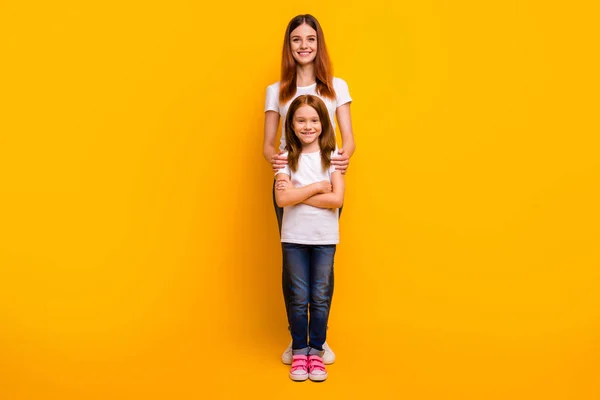 Full size photo of charming ladies with long hairstyle looking at camera with toothy smile isolated over yellow background — Stock Photo, Image