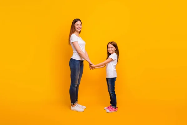 Perfil de corpo inteiro foto lateral de mãe alegre com seu filho de mãos dadas sorrindo isolado sobre fundo amarelo — Fotografia de Stock