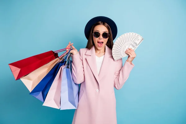 Retrato de asombrado funky millonario chica grito omg tiene beneficio puede comprar todo el día desgaste elegante abrigo gafas gafas de moda aislados sobre fondo de color azul — Foto de Stock