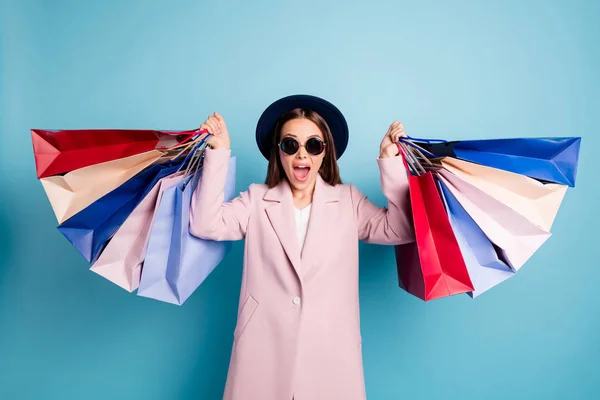 Portrait of astonished funny lady in eyewear eyeglasses go shopping find wonderful bargain hold bags scream wow omg wear season coat isolated over blue color background — Stock Photo, Image