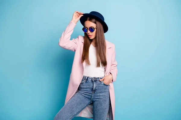 Portrait of charming stylish woman posing showing her fashionable retro suits having free time wearing pink topcoat denim jeans isolated over blue background — Stok Foto