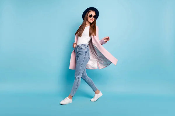 Фотографія повного тіла привабливої леді в окулярах, що ходять на набережній, вільний час, одягнений в сезон пальто джинсові джинси ізольовані на синьому фоні — стокове фото